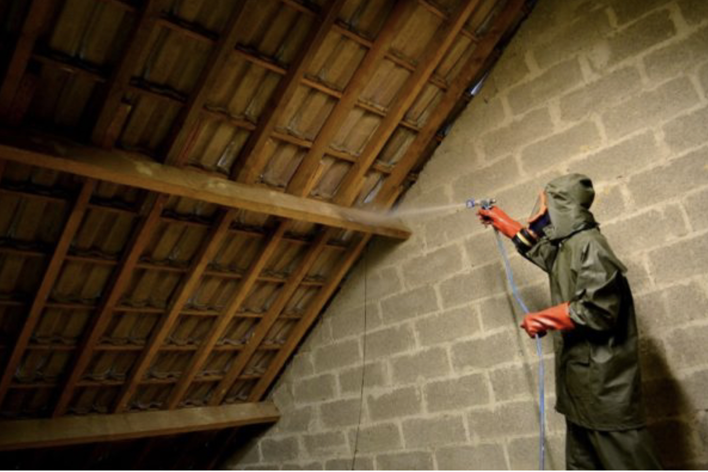 Technicien pulverisant une charpente en combles